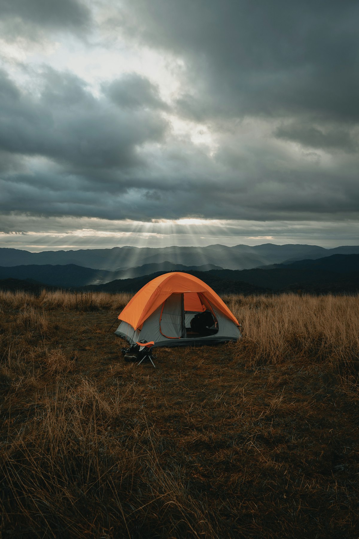 A tent on an open field under heavy cloudy skies - solo camping weather preparation
